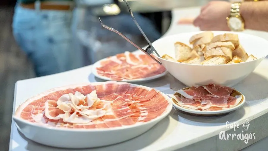 Gente comiendo jamón serrano en Café Arraigos